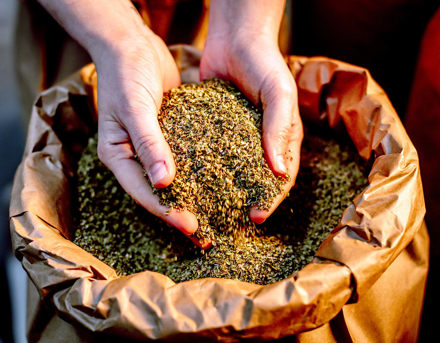 A person holding a bag of ground spices, showcasing a variety of colors and textures in the spice blend.